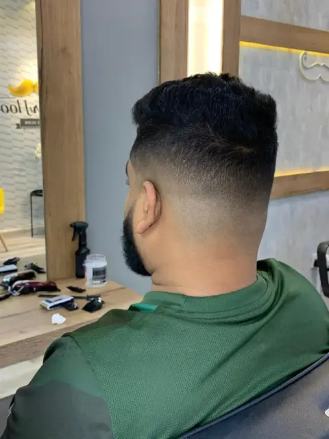 Back view of a mid skin fade blending into a dense black crop and full beard at Barberhood barbershop, JVC Dubai