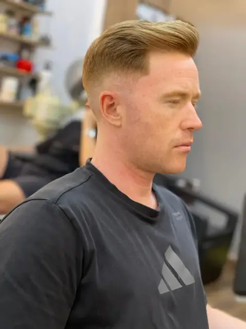 Side-swept gentleman’s cut on blond hair with a smooth high fade at Barberhood in JVC, Dubai