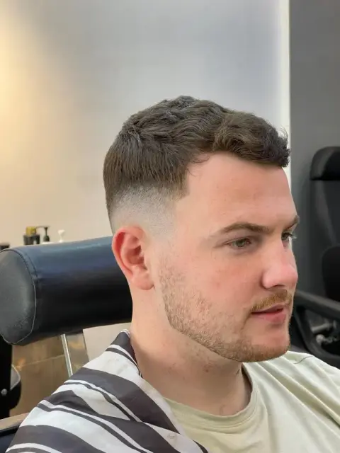 Wavy textured crop with a mid fade and blended beard line, cut at Barberhood barbershop in JVC, Dubai