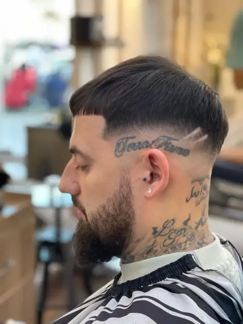 Edgar-style cropped fringe with a razored part design and high skin fade into a full beard at Barberhood, JVC Dubai