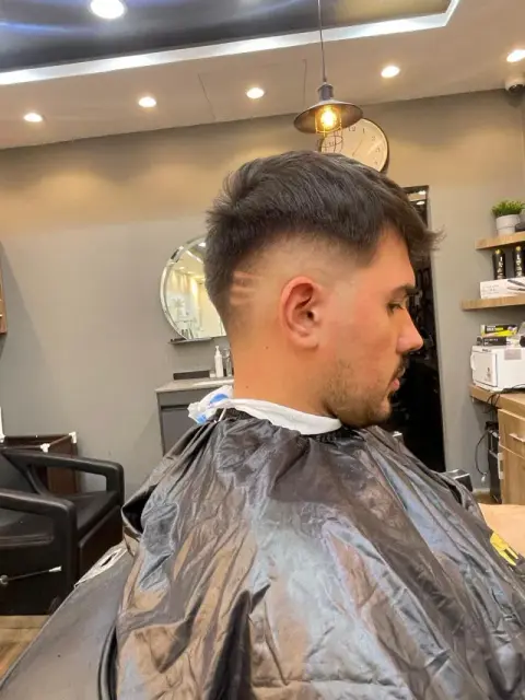 Textured crop with a mid fade and razored hair-design lines at Barberhood men’s salon in JVC, Dubai